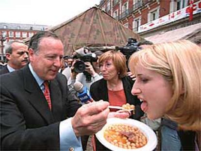 El alcalde, José María Álvarez del Manzano, ofrecía ayer un poco de su plato de cocido a una mujer.