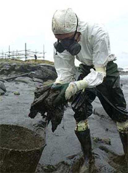 Voluntarios venidos de toda España limpian el petróleo en las rocas de A Pedriña, en la costa de Muxía.