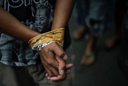 Detalle de las manos atadas con cinta de uno de los detenidos en una redada.