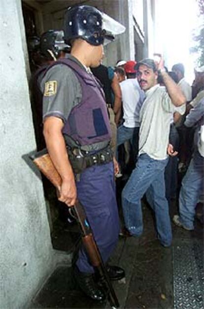 Un policía vigila la cola de clientes en un banco en Caracas.