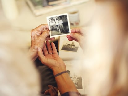 Dos personas observan fotos familiares antiguas.