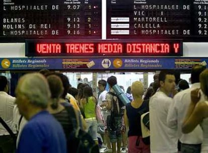 Usuarios del tren, ayer, en la estación de Sants, bajo los paneles informativos.