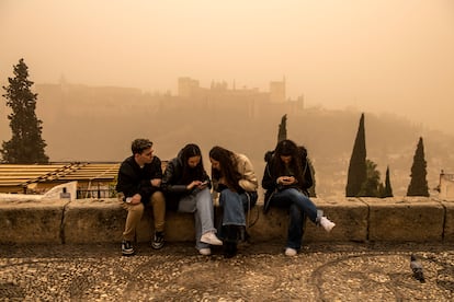 Cuatro jóvenes miran sus móviles en Granada