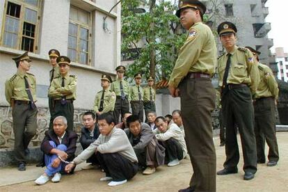 Policas chinos vigilan a traficantes de droga momentos antes de celebrarse el juicio que conden a muerte a cinco de ellos en abril de 2001.