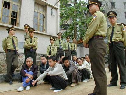 Policías chinos vigilan a traficantes de droga momentos antes de celebrarse el juicio que condenó a muerte a cinco de ellos en abril de 2001.