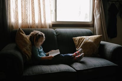 Una niña lee en el sillón. 