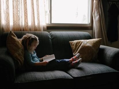 Una niña lee en el sillón. 