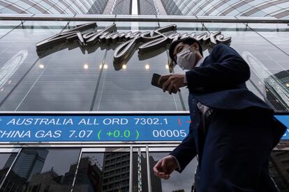 A pedestrian passes by the Hong Kong Stock Exchange electronic screen in Hong Kong on Monday, March 13, 2023.