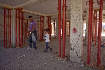 Chunhid Lachehabi y su hija caminan entre los pilares del edificio donde viven, dañados por el terremoto de hace un año.