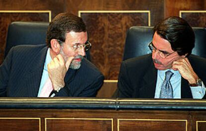 El vicepresidente primero y portavoz del Gobierno, Mariano Rajoy, conversa durante el pleno con José María Aznar.