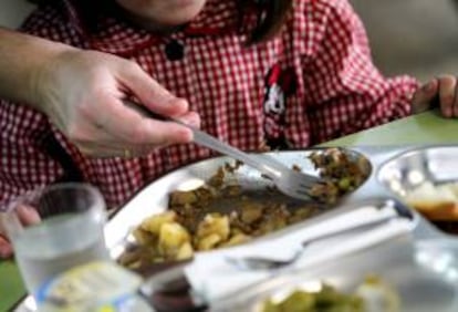 Una madre ayuda a dar de comer a los niños en un colegio público durante una huelga de los monitores de los comedores escolares. EFE/Archivo