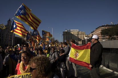 Varias personas sujetan una bandera de España mientras ven pasar a los manifestantes de la marcha contra el juicio del 'procés' por el centro de Madrid.