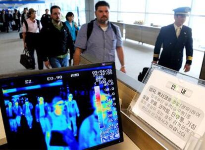 Unos viajeros pasan por un control de temperatura corporal en el aeropuerto de Seúl (Corea del Sur).