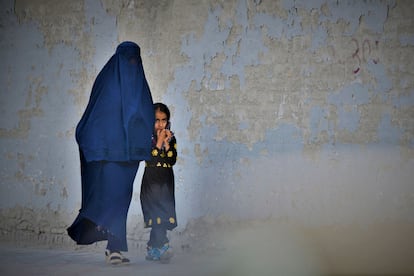 A woman in a burqa and a girl walk through Kabul in May 2022.