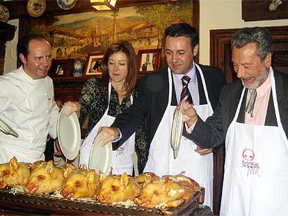 De izquierda a derecha, el hostelero Cándido López instruye en la tarea de partir el cochinillo a los periodistas Pepa Fernández, José Ribagorda y Luis del Val.