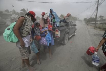 Una familia evacua a terrenos más seguros mientras el volcán Taal continúa arrojando cenizas en Lemery, Batangas (Filipinas), el lunes 13 de enero.