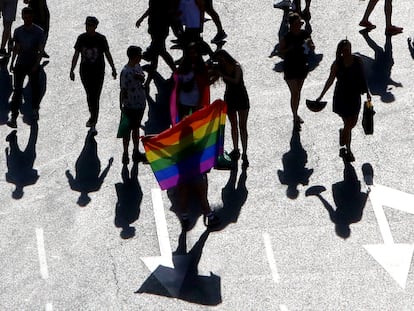 Varias personas con una bandera arcoíris, en el desfile del Día del Orgullo Gay en Madrid.