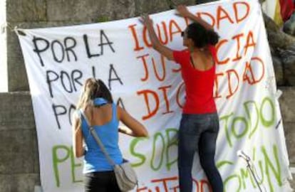 Dos integrantes del Movimiento 15-M colocan una pancarca en la Alameda de Pontevedra donde celebraron una asamblea.La Coordinadora del 15M, dentro de la campaña de protestas y acciones "Mayo Global", ha convocado manifestaciones en una docena de ciudades.