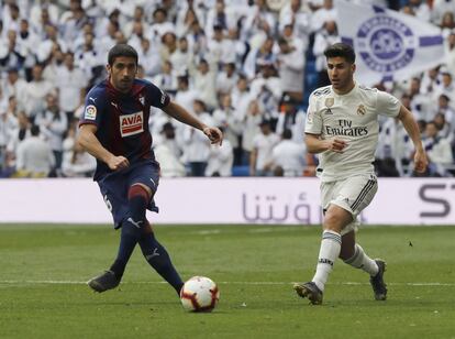 El centrocampista del Real Madrid Marco Asensio (derecha) disputa el balón al defensa del Eibar 'Cote'.