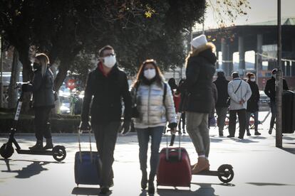 Dos personas se mueven en patinete eléctrico por las aceras de la glorieta de Carlos V de Madrid.