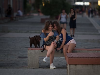 Dos adolescentes miran un teléfono tras tomar una foto en una calle de Tesalónica (Grecia).