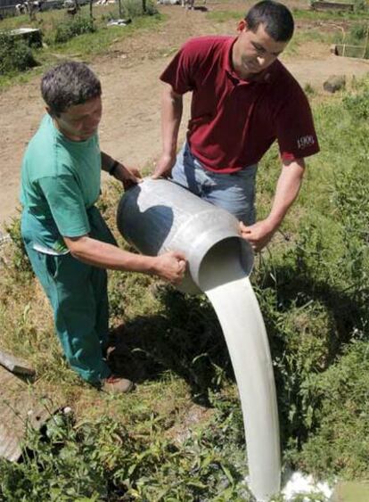 Dos ganaderos tiran leche que no pueden almacenar debido a la huelga del transporte, en la localidad coruñesa de Frades.