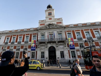 Un turista fotografía la fachada de la Real Casa de Correos, sede de la Presidencia del Gobierno de la Comunidad de Madrid, con dos lonas en apoyo al Leopoldo López.