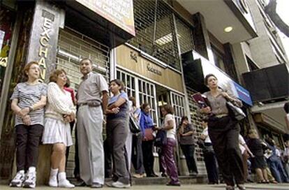 Varios vecinos de Caracas aguardan a la apertura de una oficina de cambio.