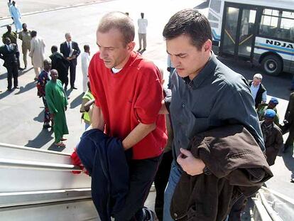 El responsable del Arca de Zoé, Eric Breteau (izquierda), sube al avión en Chad acompañado de un funcionario francés.