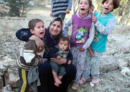 Una mujer siria y sus hijos lloran entre las casas destruidas en la ciudad de Azaz de Alepo. Cuatro personas murieron y muchas otras resultaron heridas en el ataque aereo del Ejército Sirio.