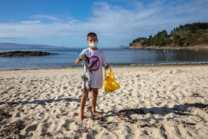 Héctor Osorio, de ocho años, muestra la basura que ha recogido en la playa de Limens (Pontevedra).