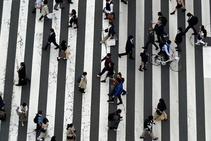 People walk along a pedestrian crossing at Ginza shopping street on March 31, 2023, in Tokyo.