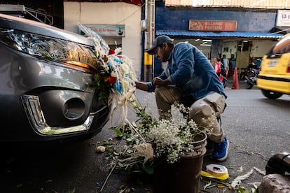 Enrique Peña decora un carro al occidente de Medellín. Él y su esposa trabajan en una floristería local, especializándose en la decoración de vehículos para la celebración del Día de la Virgen del Carmen. Ambos migraron a finales de 2024 desde Santander, al norte de Colombia, donde también se dedicaban a esta labor.