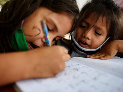 Keyla Vera (izq.) le enseña a Ariana Rodríguez matemáticas básicas durante las clases con Denisse Toala, una estudiante de 16 años, imparte debajo de un árbol a los que no pudieron asistir a clases virtuales durante la pandemia, en Guayaquil, Ecuador.