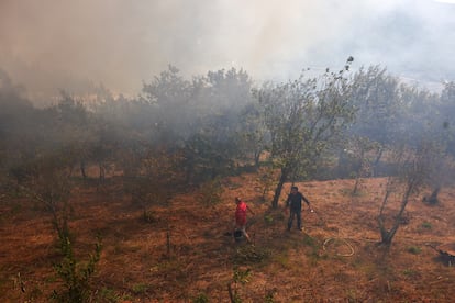 Varias personas tratan de humedecer la zona durante el incendio en Vilarinho, Portugal, este martes.