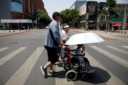 Pedestrians cross a road on a hot day amid an orange alert for heatwave, in Beijing, China June 16, 2023.