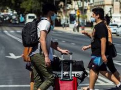 Varios turistas con maletas caminan por el centro de Málaga.