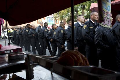 La policía espera en la fila junto a un puesto de comida para votar por gobernador en un colegio electoral en Chimalhuacán, Estado de México.