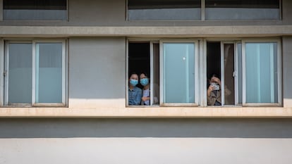 Um grupo de mulheres com máscaras olha do Hospital Jinjiantang, em Wuhan.