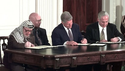 El primer ministro israelí, Benjamín Netanyahu (a la derecha de la imagen), firma en la Casa Blanca los acuerdos con Yasir Arafat, el 23 de octubre de 1998, en presencia del presidente de EE UU, Bill Clinton, y el rey Hussein de Jordania.