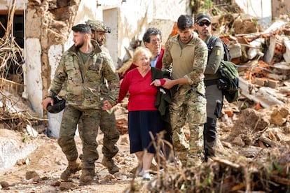 Unos militares acompañana a una de las personas mayores rescatadas en Letur (Albacete)