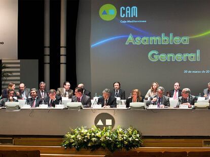 El presidente de Banco Base, Modesto Crespo, en el centro, y a su izquierda la directora general de la CAM, María Dolores Amorós, en la asamblea de la entidad, ayer en Alicante.