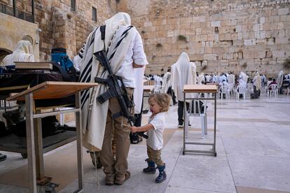 Un niño toca el fusil de un miembro de las fuerzas de seguridad israelíes frente al Muro de las Lamentaciones, este martes en Jerusalén (Israel). 