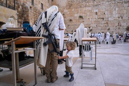 Un niño toca el fusil de un miembro de las fuerzas de seguridad israelíes frente al Muro de las Lamentaciones, este martes en Jerusalén (Israel).