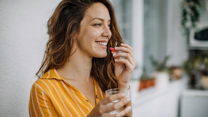 Mujer tomando un comprimido con un vaso de agua.