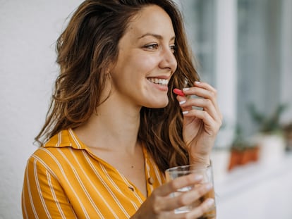 Mujer tomando un comprimido con un vaso de agua.