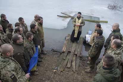 Solo en Moscú, cerca de 90.000 personas se han sumergido en las aguas heladas según declaraciones de la policía de la capital rusa. En la imagen, un sacerdote militar bendice el agua mientras los soldados observan el ritual sosteniendo la bandera nacional durante las celebraciones de la Epifanía en el pueblo Lebedynske, cerca de Mariúpo (Ucrania).