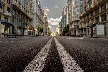 Una mujer espera al autobús en una solitaria Gran Vía