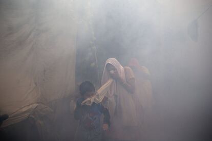 Residentes de Nueva Delhi (India) se protegen del humo tras ser fumigada una zona residencial para evitar que los mosquitos se reproduzcan.