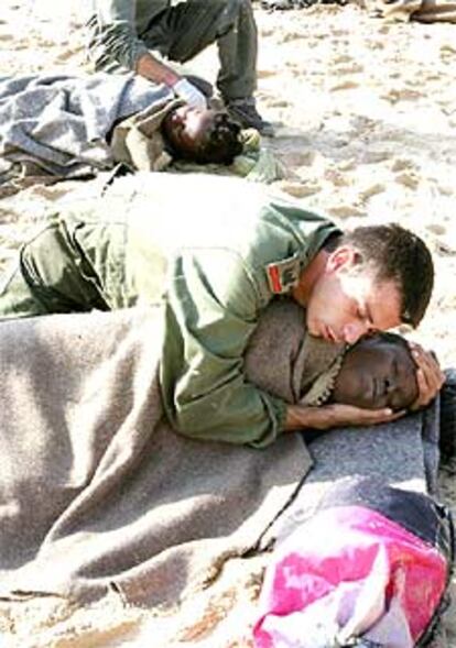 Miembros de la Guardia Civil y del Ejército abrigan y dan calor con su cuerpo a dos inmigrantes en Tarifa.